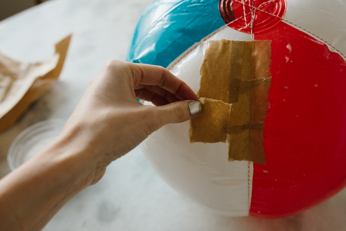 applying paper mache strips to a beach ball